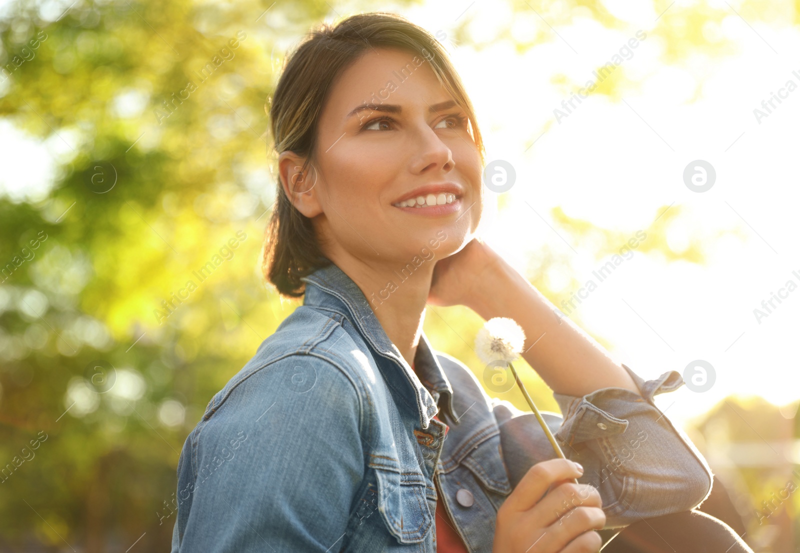 Photo of Young woman with dandelion in park on sunny day. Allergy free concept