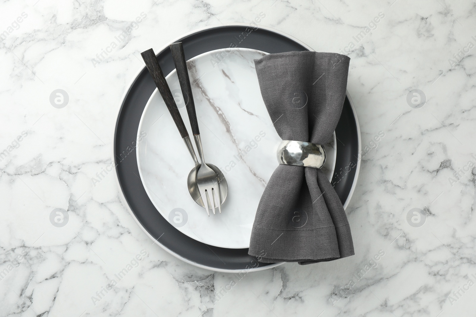 Photo of Stylish setting with cutlery, napkin and plates on white marble table, top view