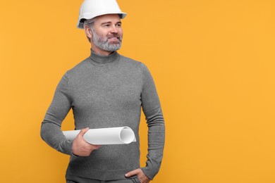 Photo of Architect in hard hat holding draft on orange background. Space for text
