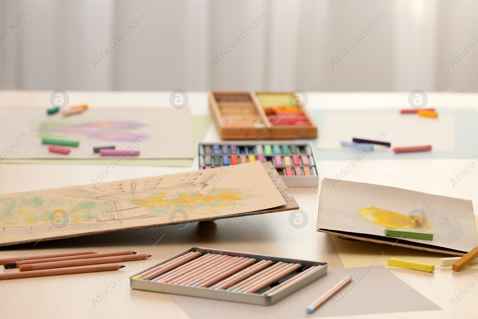 Photo of Artist's workplace with drawings, soft pastels and color pencils on table indoors