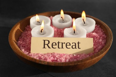 Photo of Retreat concept. Bowl with sea salt, card and burning candles on dark grey table, closeup