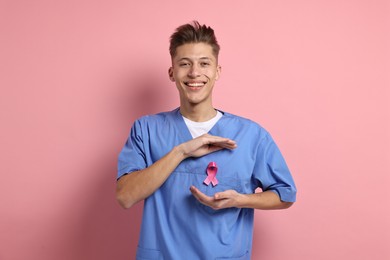 Photo of Mammologist with pink ribbon on color background. Breast cancer awareness