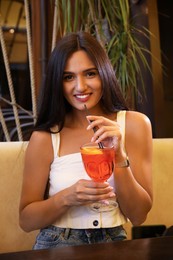 Photo of Young woman with Aperol spritz cocktail resting at restaurant