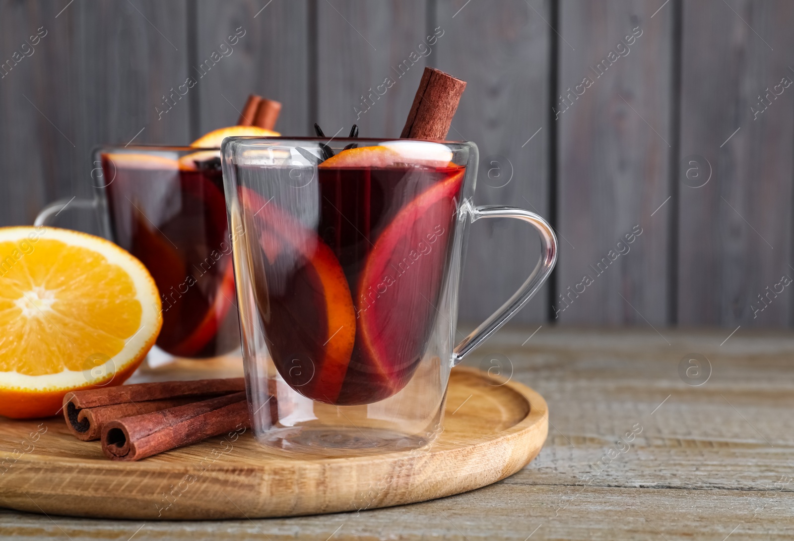 Photo of Aromatic mulled wine in glass cups on wooden table