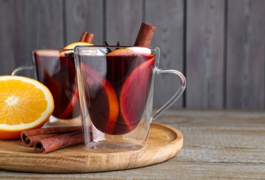 Photo of Aromatic mulled wine in glass cups on wooden table