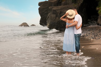 Photo of Young couple on beach near sea, back view. Space for text