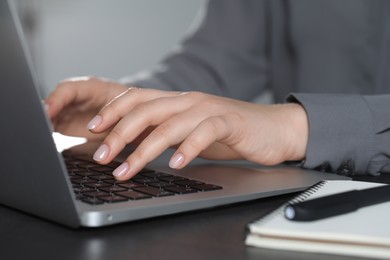 Photo of Woman typing on laptop at table, closeup. Electronic document management