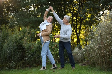 Photo of Affectionate senior couple dancing together in park. Romantic date