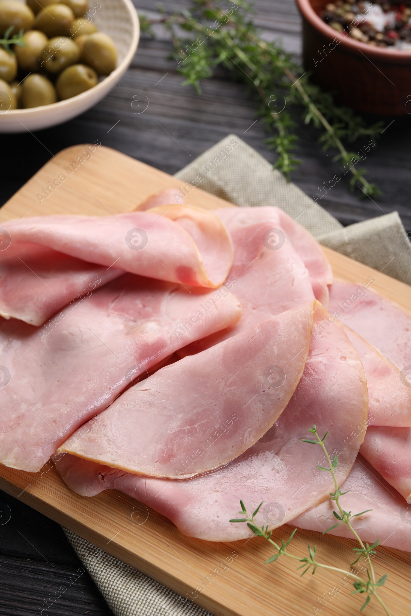 Photo of Slices of delicious ham with thyme on dark wooden table