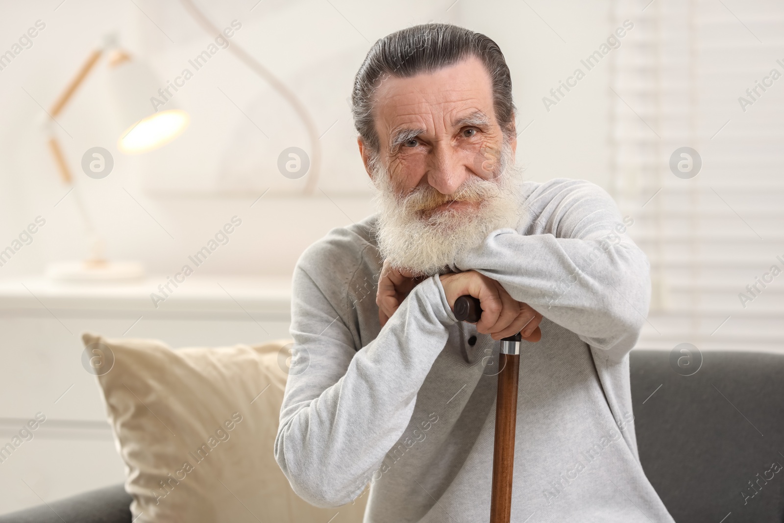Photo of Senior man with walking cane on sofa at home