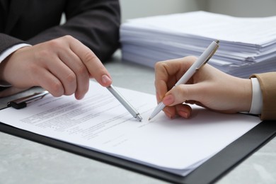 Photo of Woman signing document at table in office, closeup