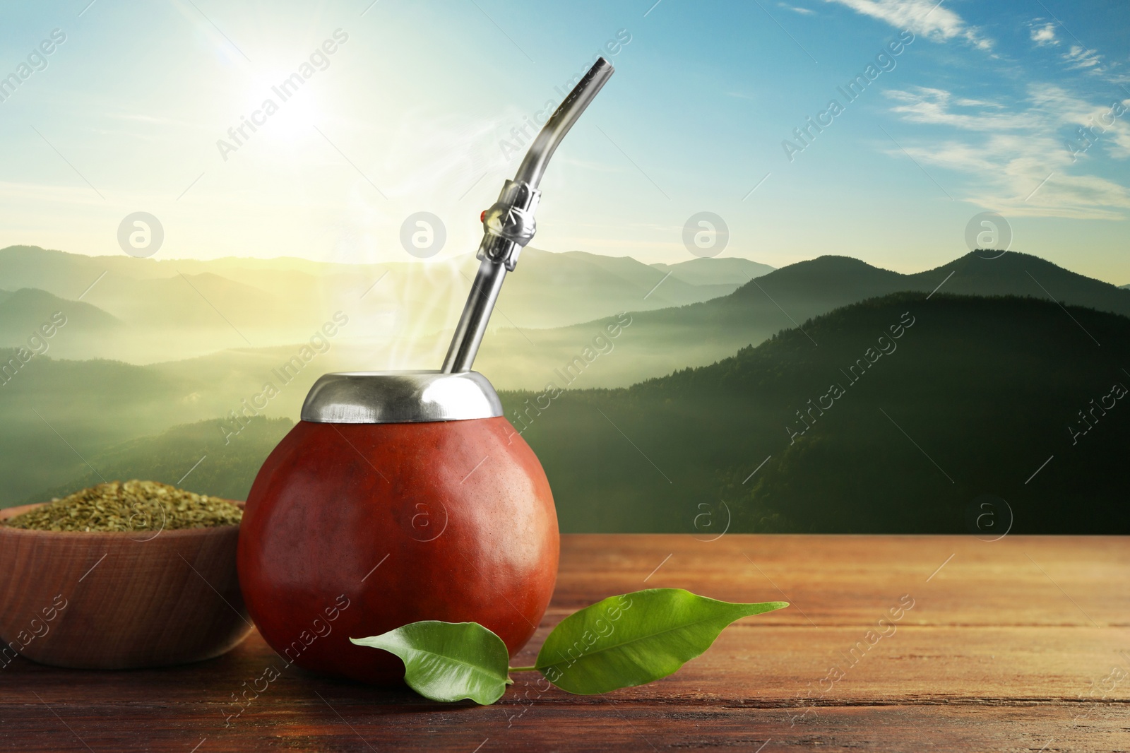 Image of Calabash with mate tea and bombilla on wooden table and beautiful view of mountain landscape, space for text