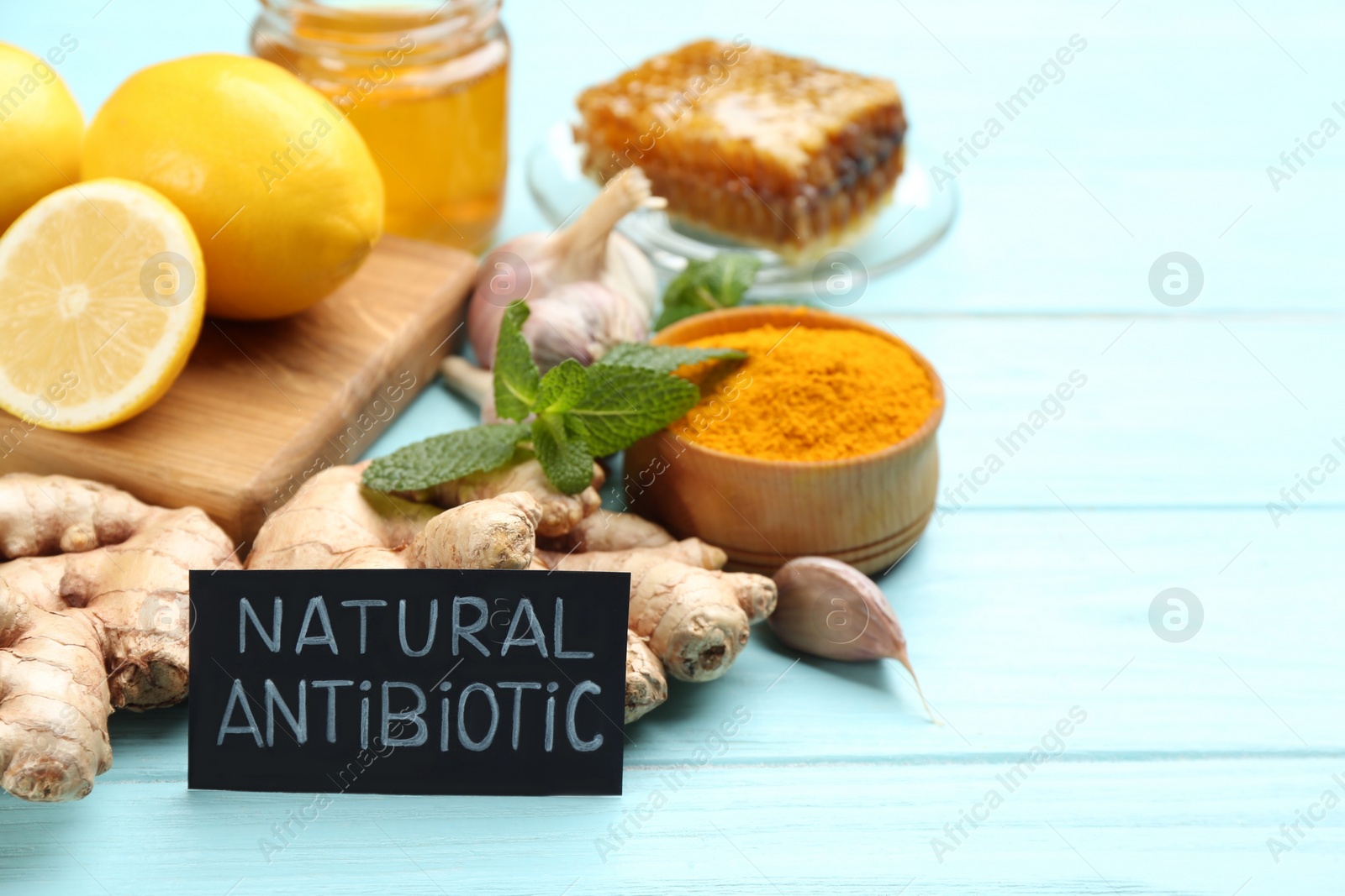 Photo of Different fresh products and card with phrase Natural Antibiotic on light blue wooden background, space for text