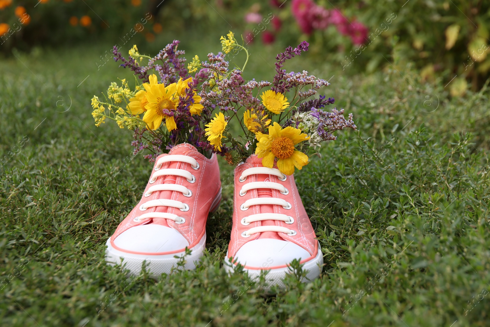 Photo of Shoes with beautiful flowers on grass outdoors