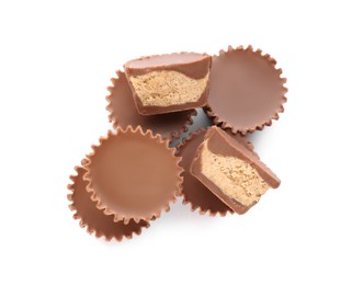 Cut and whole delicious peanut butter cups on white background, top view