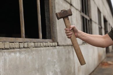 Man with sledgehammer near old building outdoors, closeup. Space for text