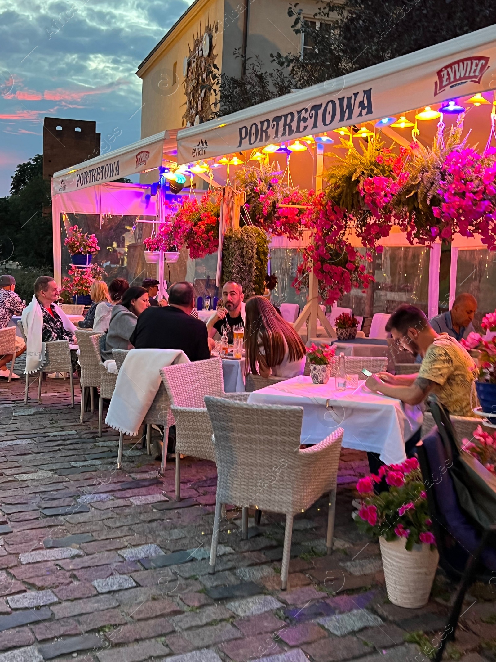 Photo of WARSAW, POLAND - JULY 15, 2022: Outdoor cafe terrace on city street in evening