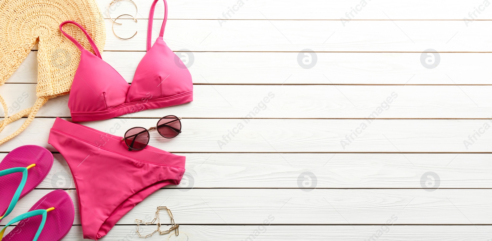 Photo of Beautiful pink bikini and beach accessories on white wooden background, flat lay. Space for text