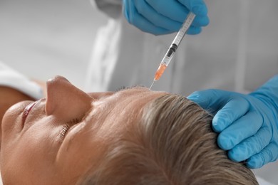 Photo of Doctor giving facial injection to senior woman in clinic, closeup. Cosmetic surgery