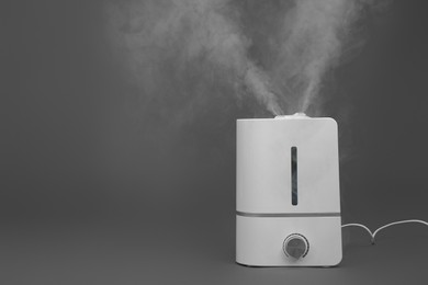 Photo of Modern air humidifier on grey background. Space for text