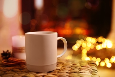 Photo of Cup of hot drink near fireplace at home. Space for text