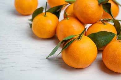 Photo of Fresh ripe tangerines with green leaves on table