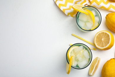 Photo of Soda water with lemon slices and ice cubes on white table, flat lay. Space for text