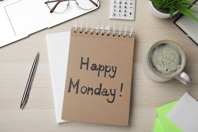 Photo of Message Happy Monday written in notebook, office stationery and cup of coffee on wooden  desk, flat lay