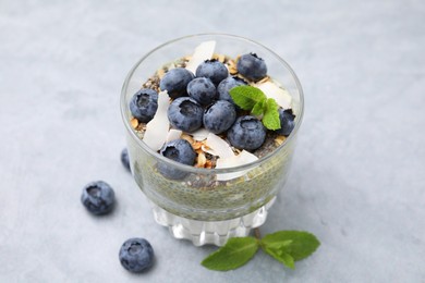 Tasty chia matcha pudding with coconut and blueberries on grey table. Healthy breakfast