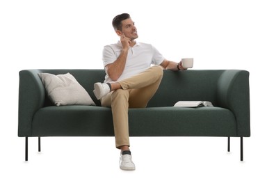 Photo of Man with cup of drink and book on comfortable green sofa against white background