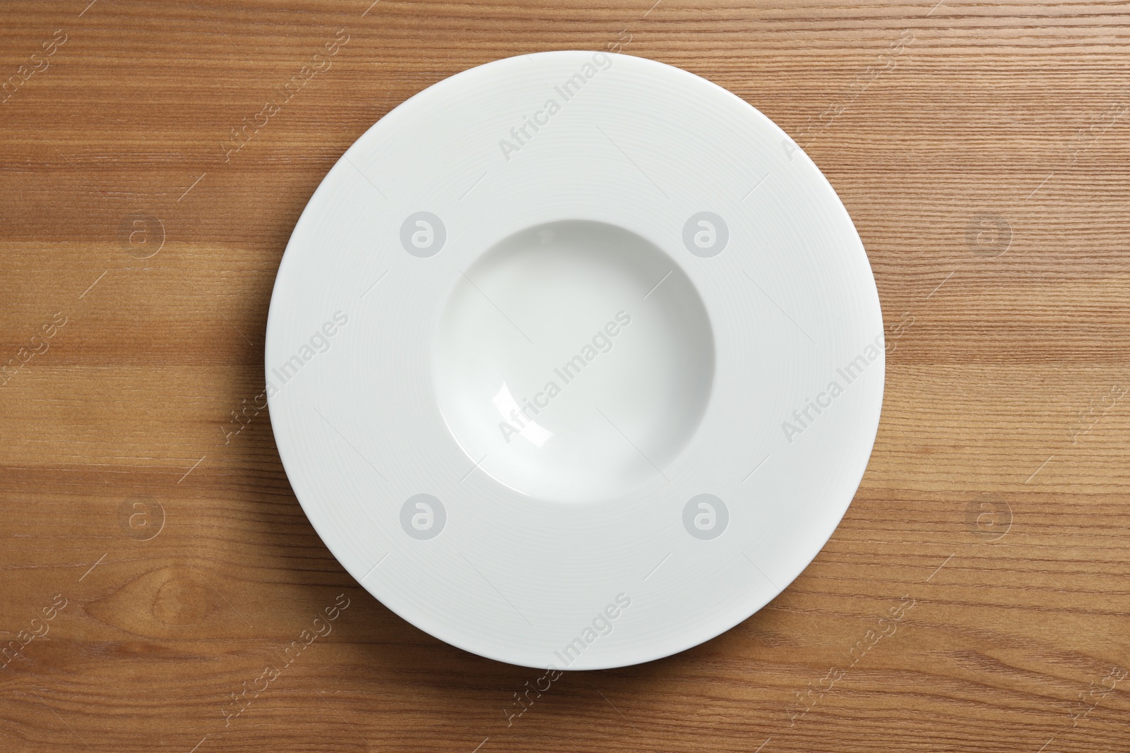 Photo of Empty ceramic plate on wooden table, top view