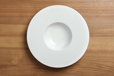 Empty ceramic plate on wooden table, top view