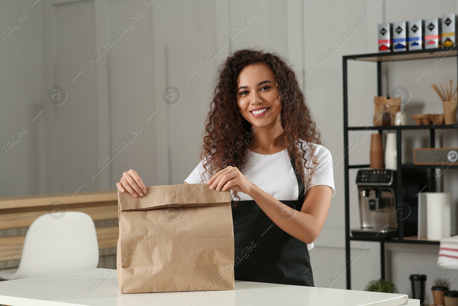 Photo of Worker with paper bag at counter in cafe