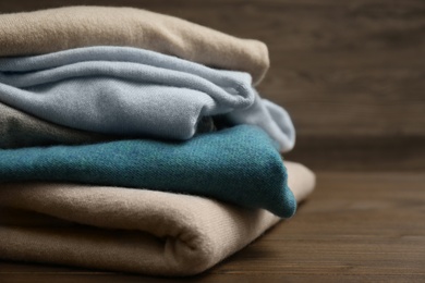 Photo of Stack of cashmere clothes on wooden background, closeup