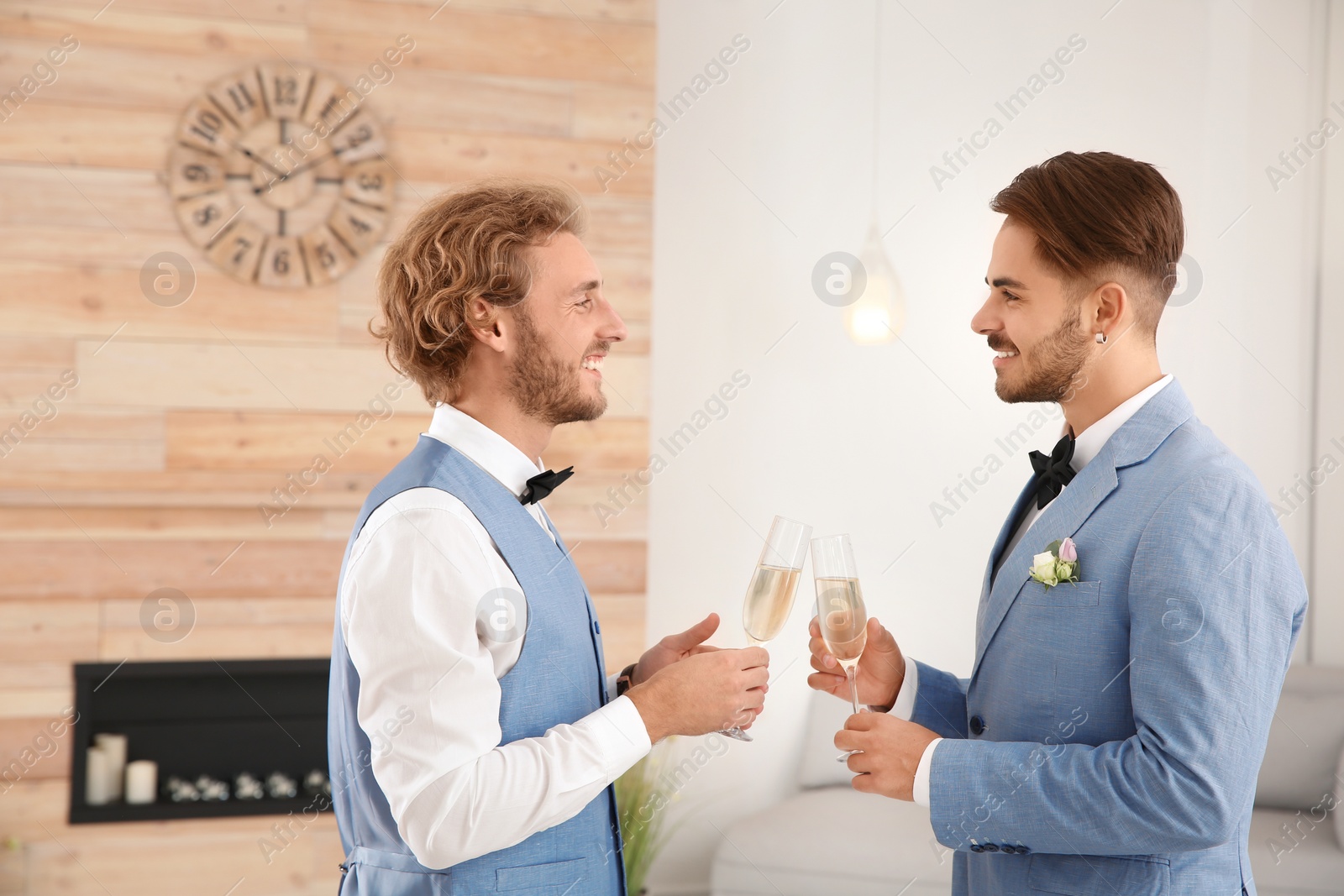 Photo of Happy newlywed gay couple with glasses of champagne at home