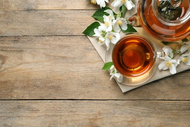 Aromatic jasmine tea and fresh flowers on wooden table, flat lay. Space for text