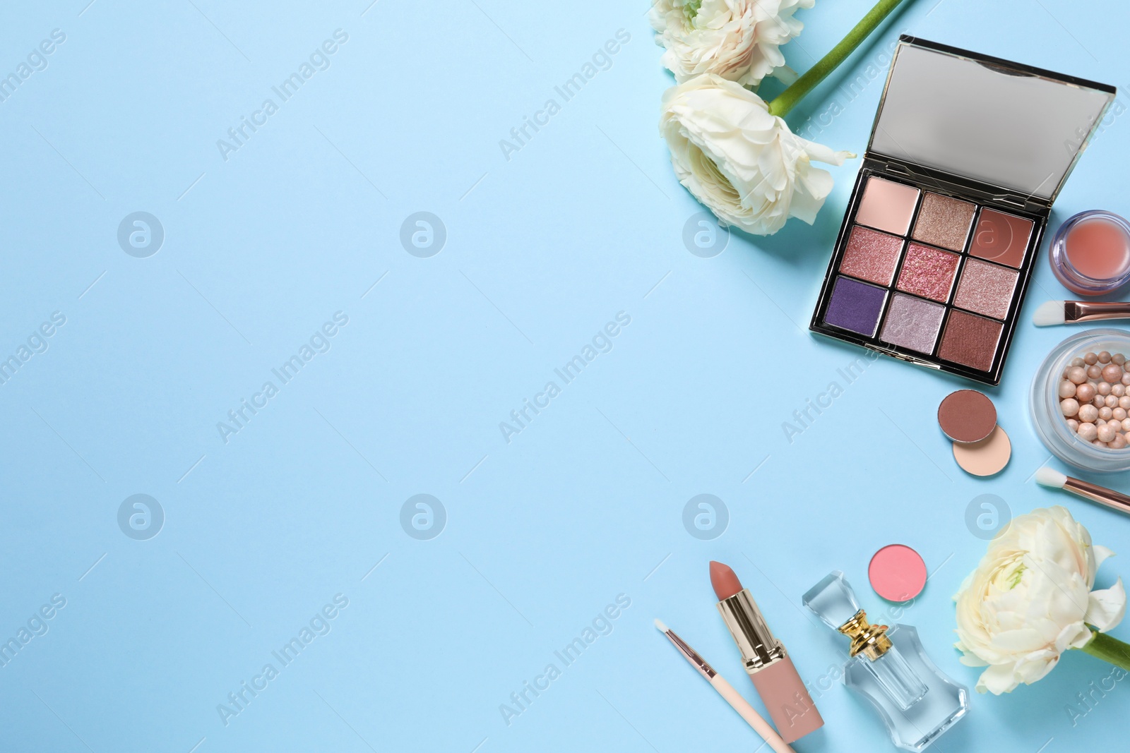 Photo of Flat lay composition with different makeup products and beautiful flowers on light blue background. Space for text