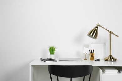 Photo of Cozy workspace with laptop, lamp and stationery on wooden desk at home. Space for text