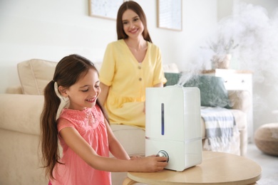 Mother and daughter near modern air humidifier at home