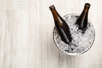 Beer in metal bucket with ice on white wooden table, top view. Space for text