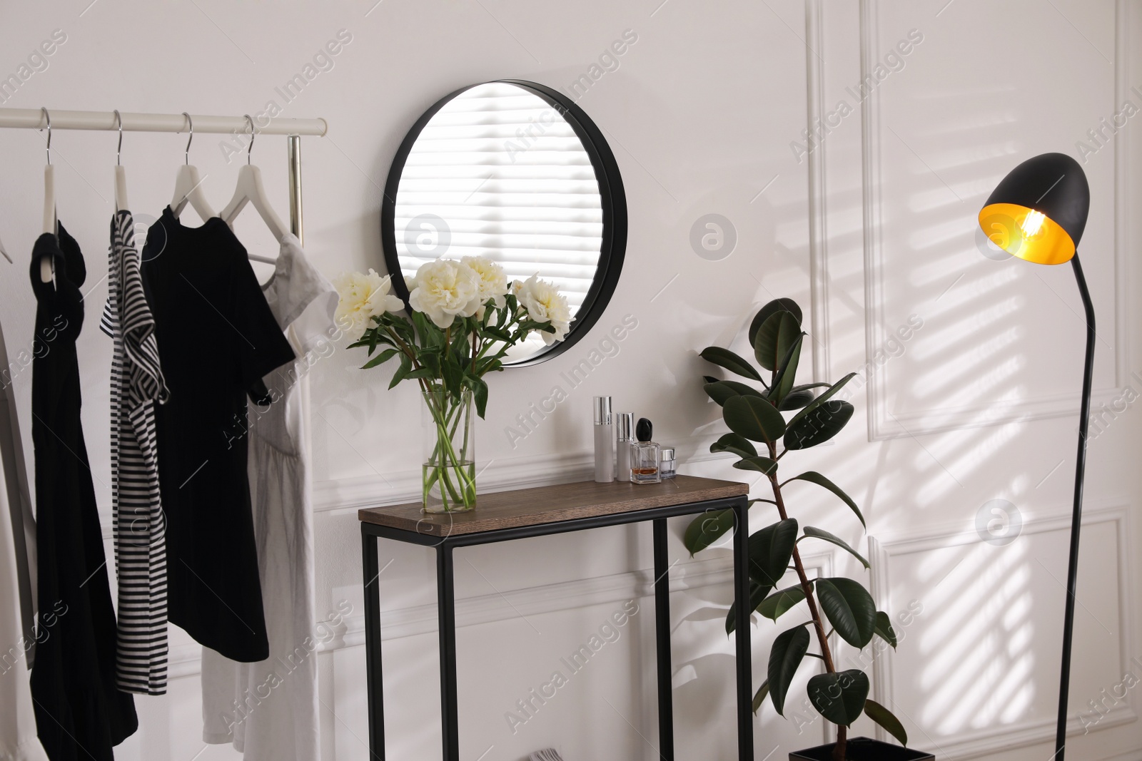 Photo of Rack with clothes near console table in room. Interior design