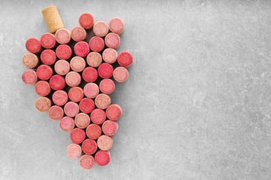 Grape made of wine bottle corks on grey table, top view. Space for text