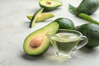 Composition with natural oil and avocados on grey stone background