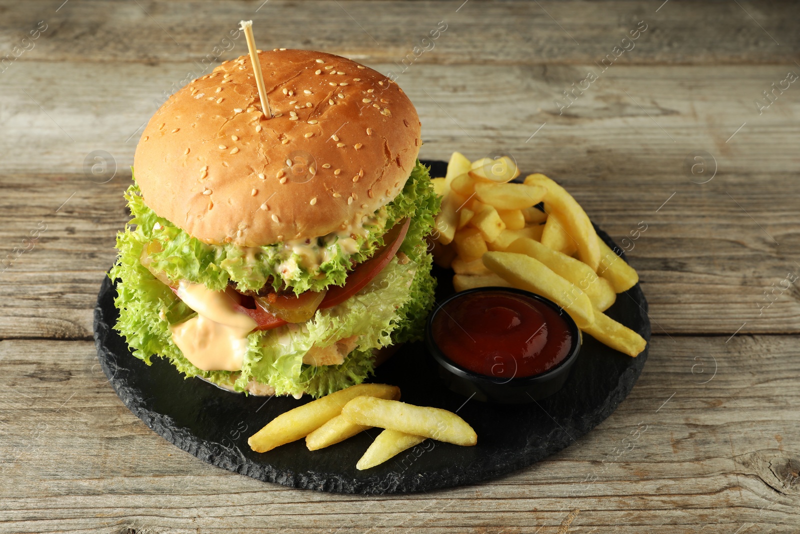 Burger with delicious patty, french fries and sauce on wooden table Photo of Burger with delicious patty, french fries and sauce on wooden table