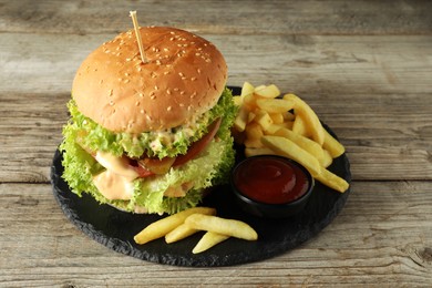Photo of Burger with delicious patty, french fries and sauce on wooden table