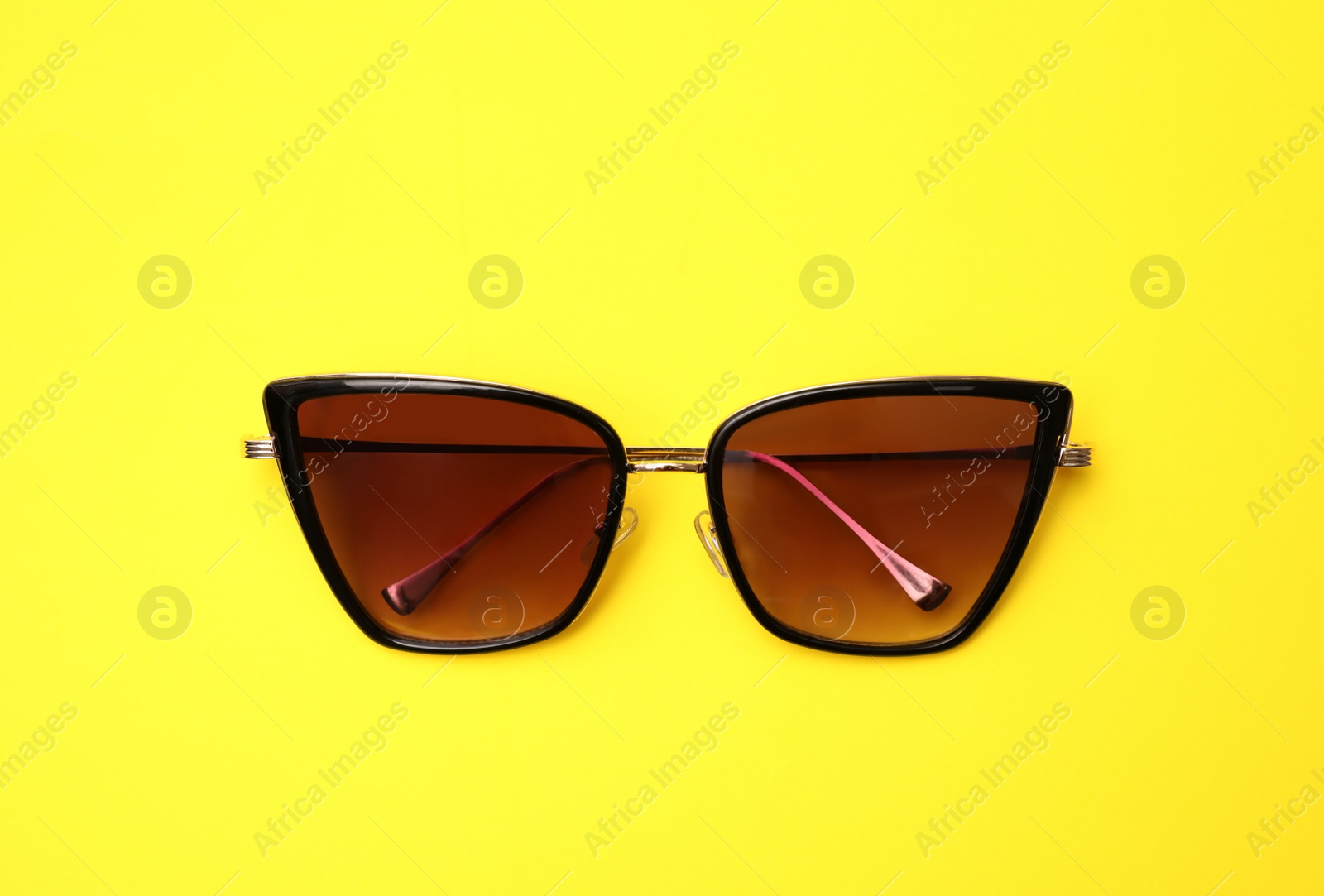 Photo of Stylish sunglasses on yellow background, top view