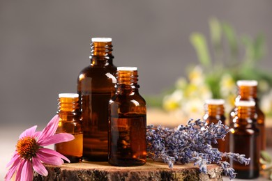 Photo of Bottles with essential oils and flowers on blurred background, closeup