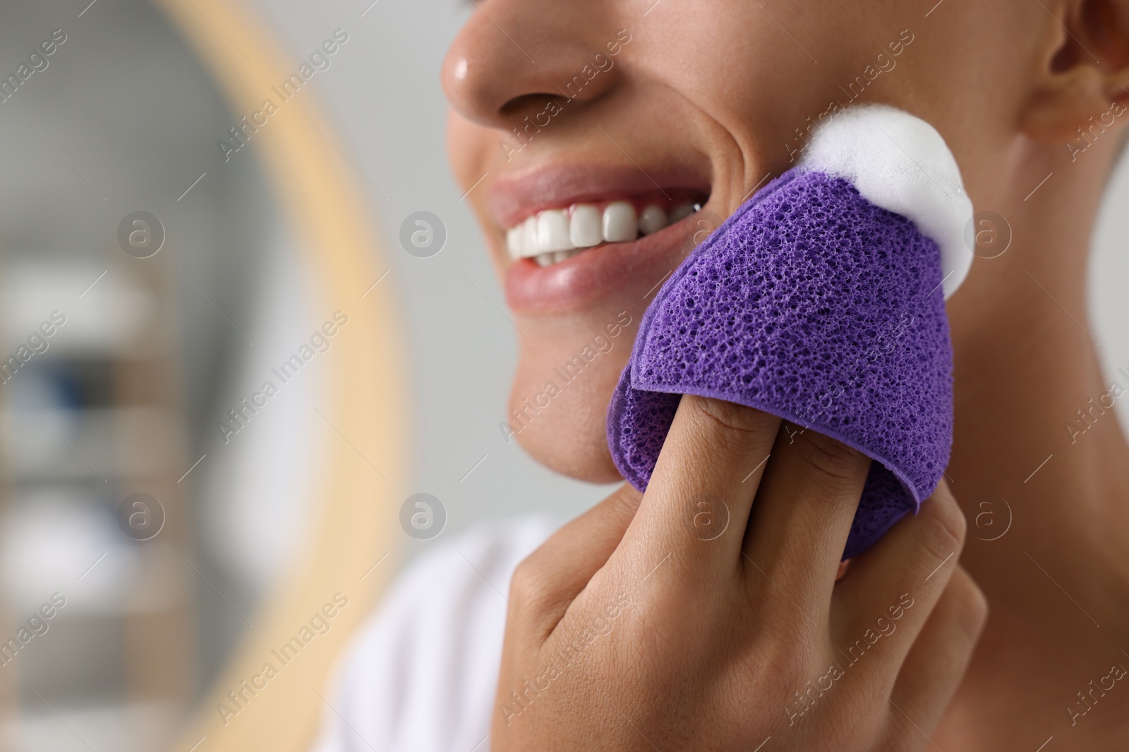 Photo of Happy young man washing his face with sponge in bathroom, closeup. Space for text