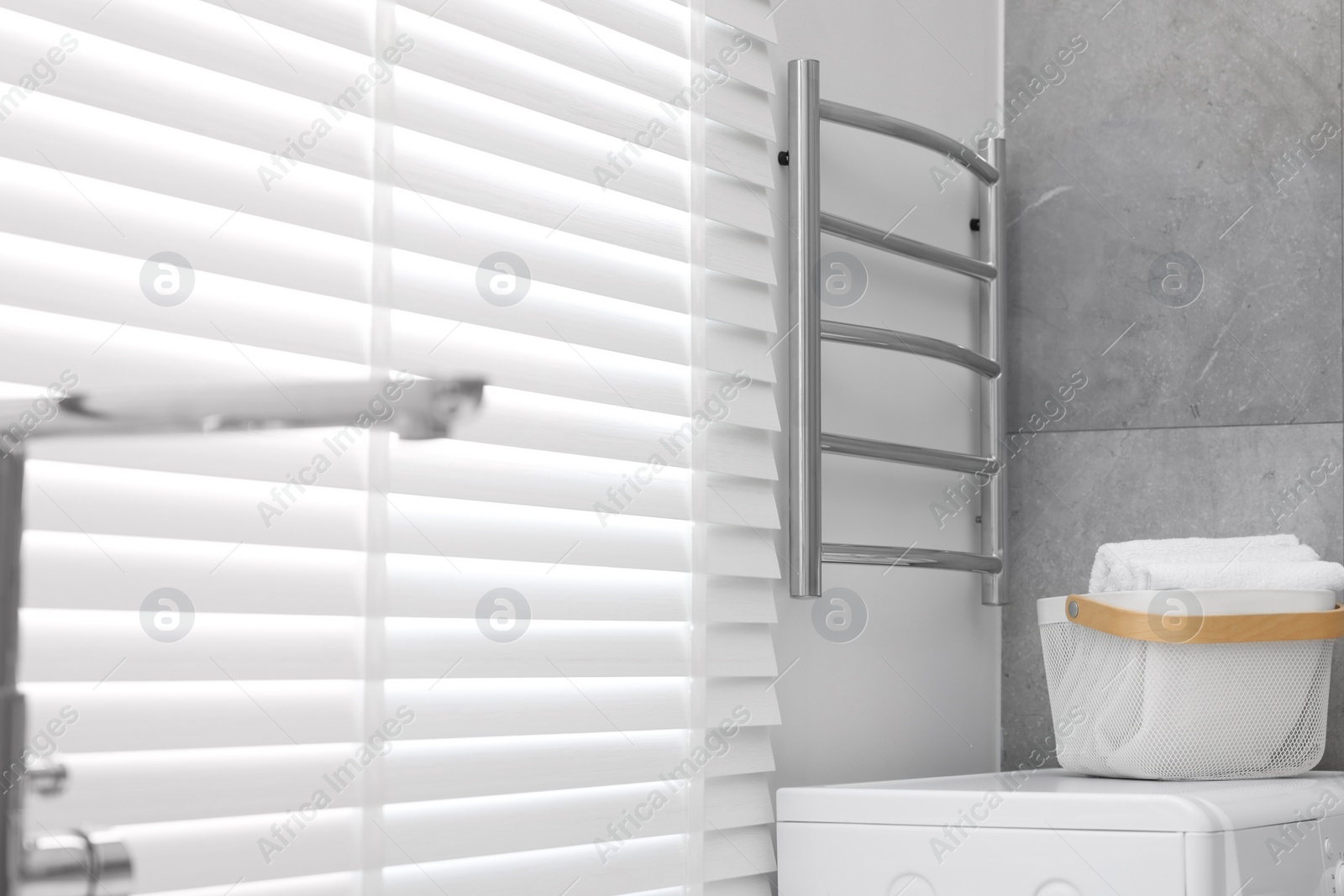 Photo of Modern heated towel rail on wall in bathroom