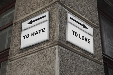Image of Sign boards with different directions - TO HATE or TO LOVE on building outdoors